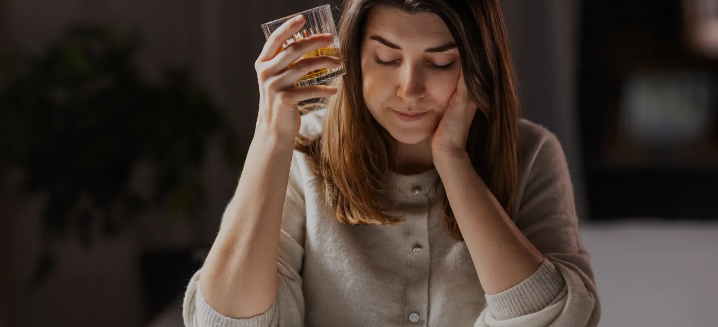 Woman holding alcoholic beverage in hand looking stressed and in need of support