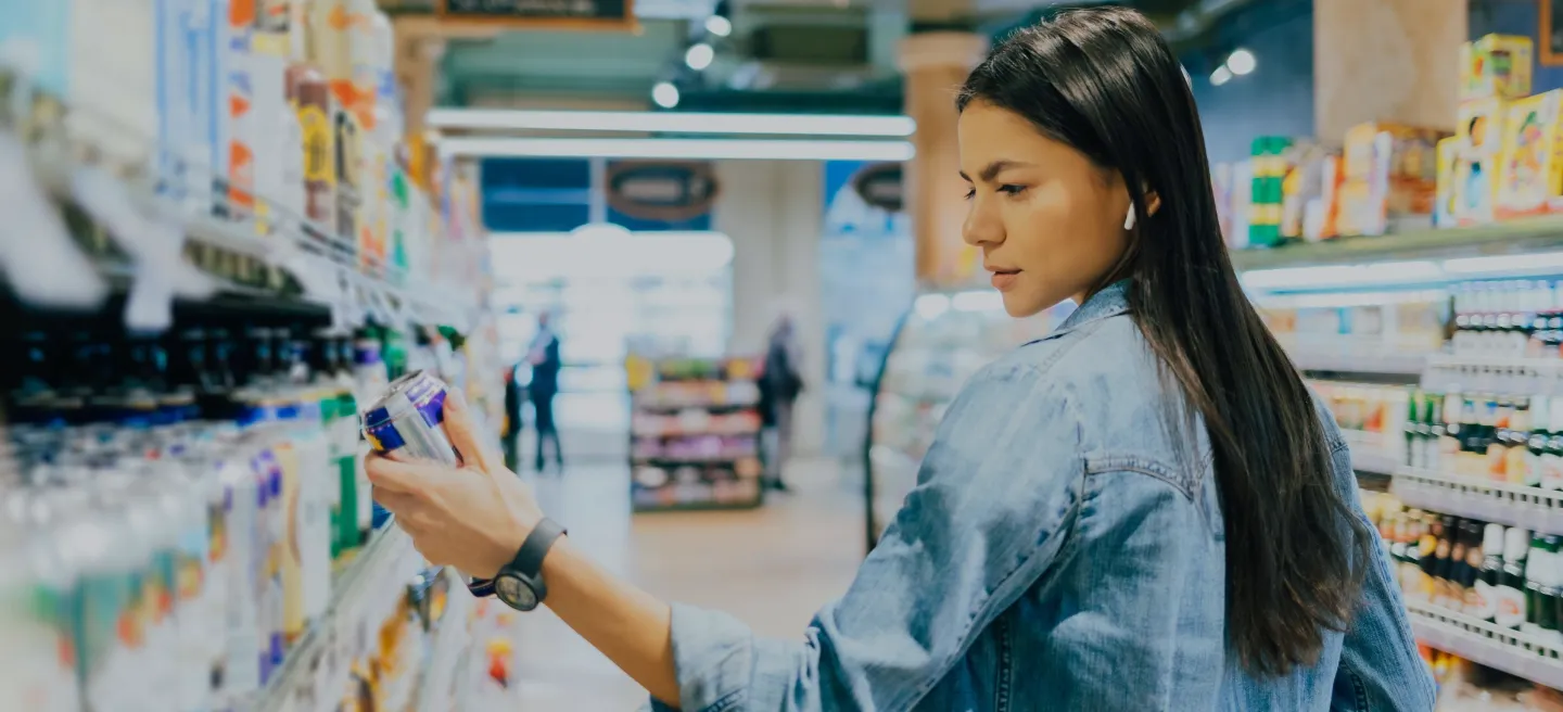 Young woman examines alcoholic beverage in the isle of a retail store